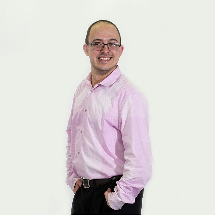 Michael Roppolo is wearing a pink shirt and smiling at the camera.